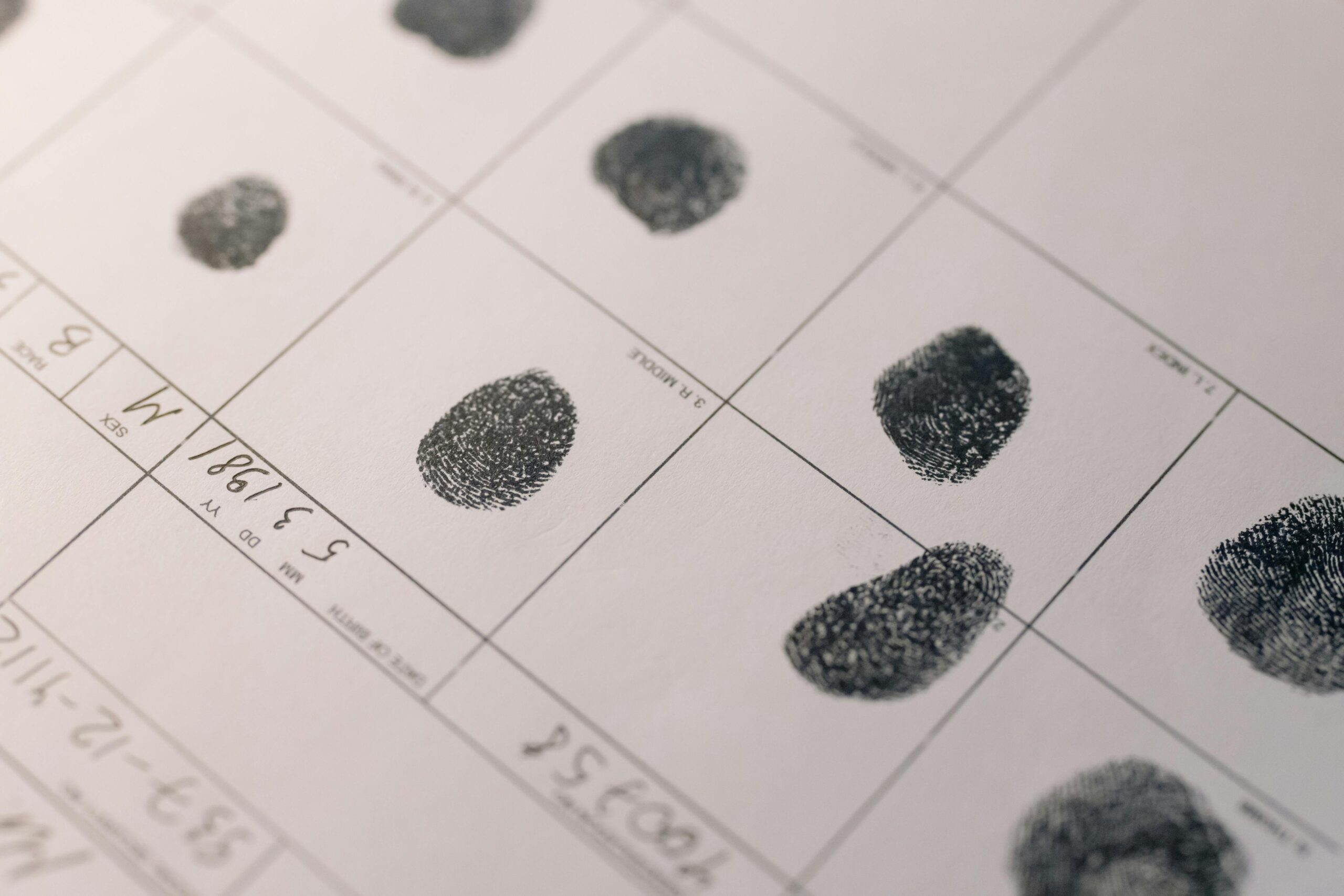 Close-up of ink fingerprints on an official document with grid lines and handwritten notations